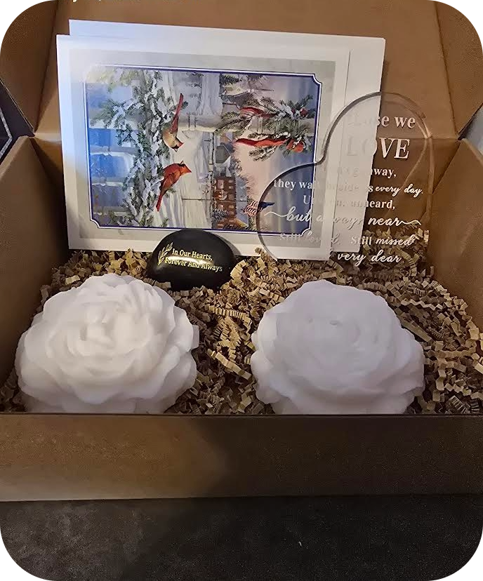 Gift box with two white flowers, a card, and a small decorative item.